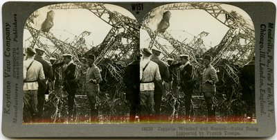 Tarjeta estereoscópica horizontal, sepia, mostrando un grupo de hombres uniformados inspeccionando los restos de un zepelín. Número de estereografía de Keystone 18632. El título dice de Keystone View Company
